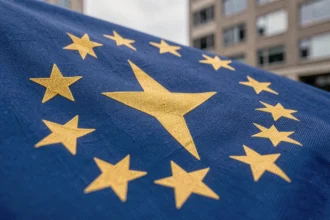Gros plan sur les étoiles dorées du drapeau européen en tissu bleu cobalt, détail textile des symboles officiels de l'Union européenne